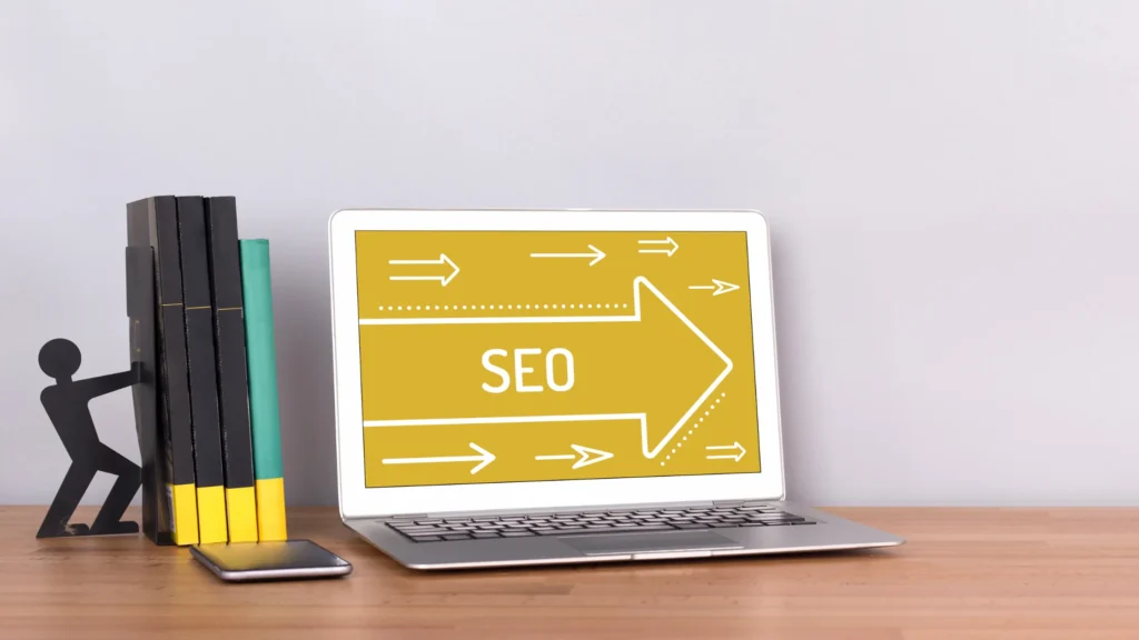 Laptop displaying "SEO" with arrows and books next to it, representing Local SEO for Churches strategy.